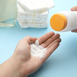 Person shaking baby powder into hand.