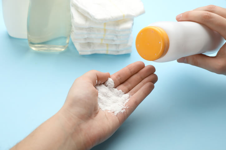 Person shaking baby powder into hand.