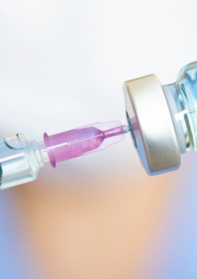 doctor's hand holds a syringe and a blue vaccine bottle at the hospital. Health and medical concepts.